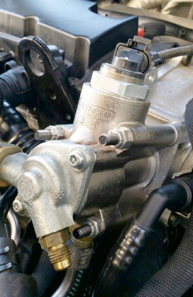 Detaillierte Ansicht eines Kraftstoffinjektors in einem Motorraum.